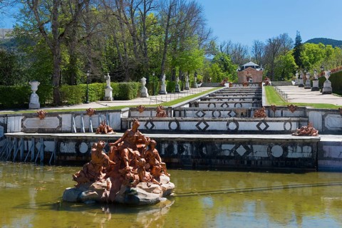 Baroque fountain with detailed sculptures in a park setting with green trees, Royal Castle La