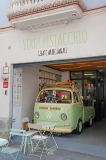 Retro ice cream parlour with green VW bus and outdoor seating in front of the shop, pedestrian