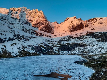 Aerial view of icy lake in front of steep mountains, winter, sunrise, Storvatnet, Flakstadoya,
