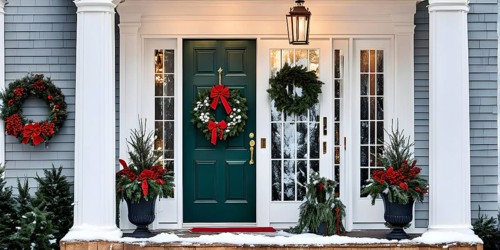 Festive front porch with holiday garlands wrapped around the columns, a wreath hanging on the door,
