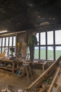 Elderly man standing on a workbench and repairing a window in a workshop, Mecklenburg-Vorpommern,