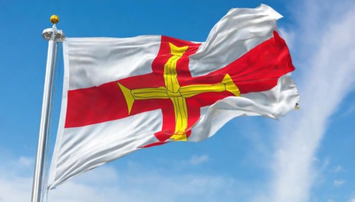 The flag of the Isle of Guernsey, Great Britain, flutters in the wind