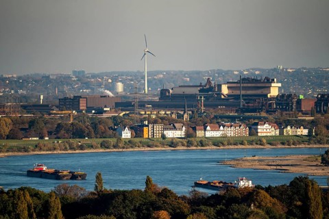 Cargo ships on the Rhine near Duisburg, houses on Deichstrasse, industrial backdrop of the