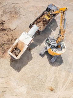 Aerial view of an excavator and a lorry working on a large construction site, demolition site,