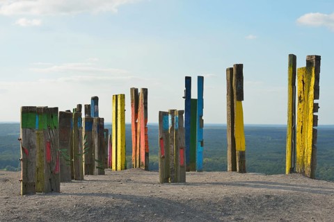 A creative art installation of colourfully painted wooden posts with abstract patterns against a