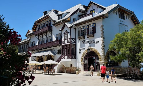 Historic white hotel with half-timbered houses, parasols and holidaymakers on a sunny day, Elafos