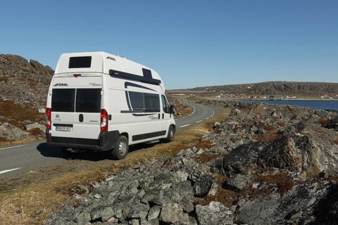 Camper/caravan on a lonely coastal road through the tundra to Hamningberg (in the background) on