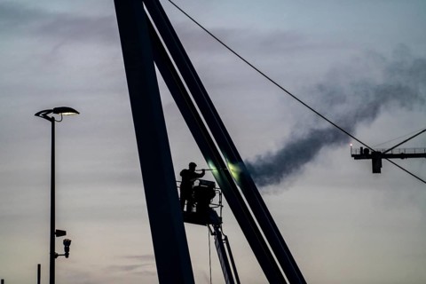 Worker cleans a bridge pier with a high-pressure cleaner on a cherry picker at the Erasmus Bridge