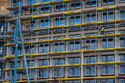 Large construction site, scaffolded shell of an office building complex, air hoses for building