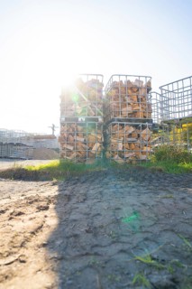 Stacked pieces of wood in metal frames in a meadow with sunshine and shade, refugee accommodation