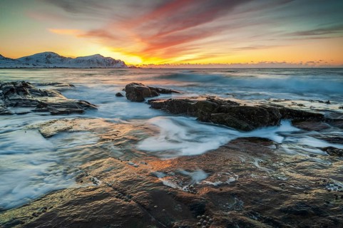 Long exposure, sunset in winter at Skagsanden, rocks washed over by the sea on the beach at