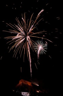 Fireworks light up the night sky above a building with glowing sparks, New Year's Eve, Stallbastei,