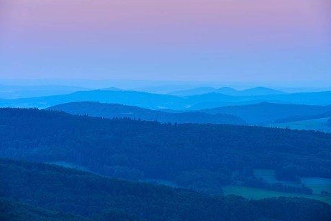 Undulating hills and mountains in blue and pink evening twilight, creating a calm and peaceful