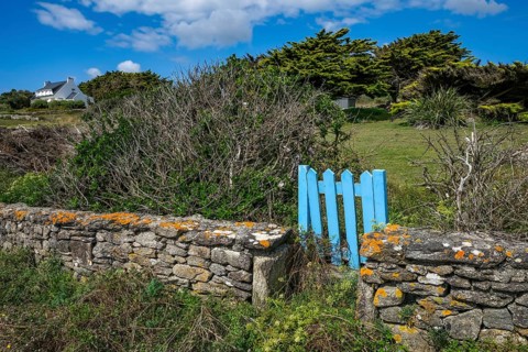 Pors Poulhan, Brittany, France - Picturesque dry stone wall with blue garden gate on the GR36