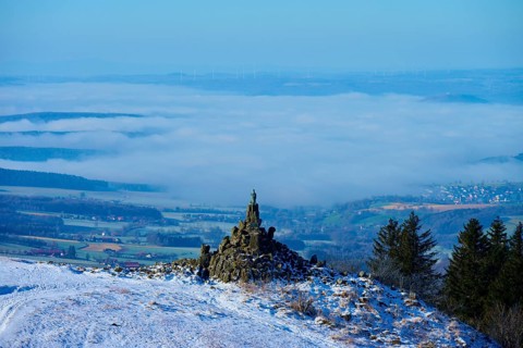 Winter landscape with snow-covered hill and aviation monument, cloudy sky and wide view,