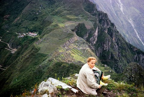 Female tourist sitting on the mountain Huayna Picchu with view of Machu Picchu, Peru, South America