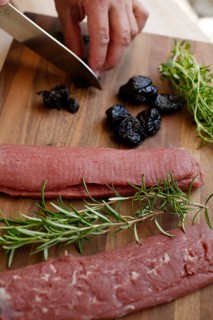 Swabian cuisine, preparation of lamb with prunes, raw lamb, rosemary, herbs, sliced garlic, lemon