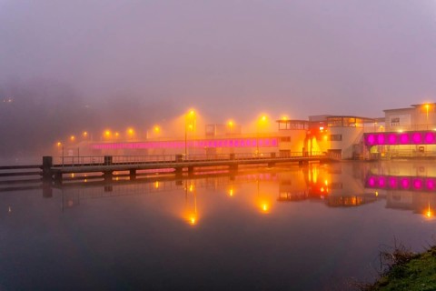 The illuminated weir of Lake Baldeney in Essen, in heavy fog, foggy weather in winter, North