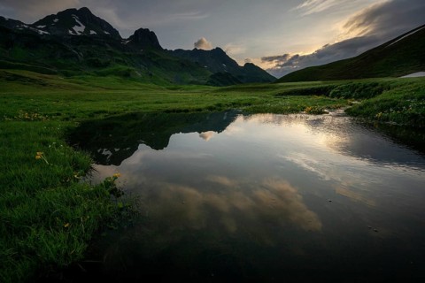 Summit in the morning light with dramatic clouds and stream in the foreground, Lech,