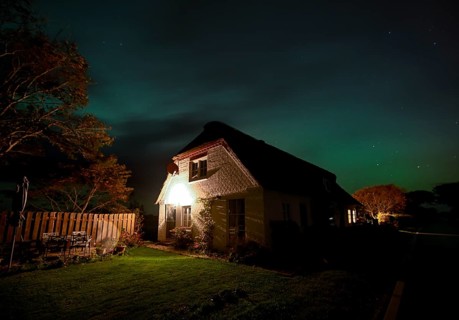 Northern Lights (Aurora borrealis) over a thatched roof house, Junkersmitteldeich, Pellworm Island,