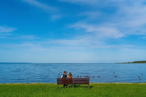Woman and girl sitting on a bench in a meadow on the shore of the Szczecin Lagoon in the village of