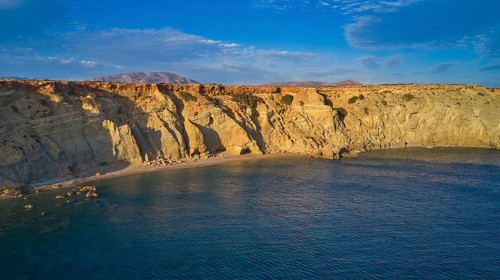 Rocky cliffs at sunset with calm water and natural beauty, drone shot, evening light, Paralia Agios