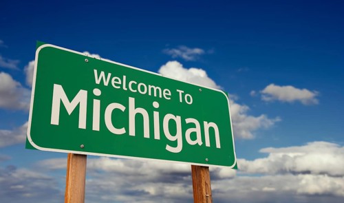 Welcome to michigan green road sign over blue sky with some clouds