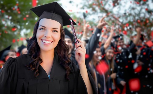 Young female graduate celebrating her graduation with her fellow classmates outdoors