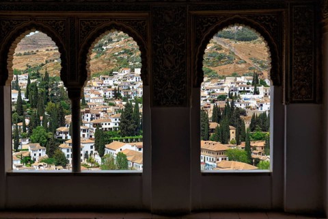 View of the city through three arabesque arched windows, Nasrid Palaces, Alhambra, Granada,