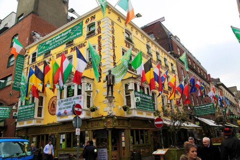 Flags outside colourful yellow Oliver St John Gogarty pub in Temple Bar area, Dublin city centre,