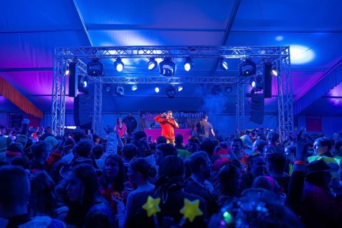 Schlagerkönig Tobee, A stage with blue lighting in a party tent full of celebrating people,