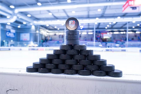 Stacked ice hockey pucks in an ice rink on the sidelines, Heilbronner Falken Vs Bietigheimer
