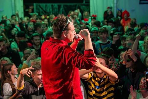Schlager king Tobee in red shirt sings on stage in front of a rousing audience, carnival,