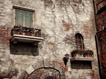 Old rustic house windows with flowers, antique architecture in Venetian style sepia toned