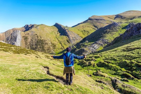 Hiker with open arms enjoying the breathtaking panorama of mount txindoki in gipuzkoa, basque