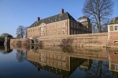 Brick castle on the water with precise reflection in the calm water, ahaus, germany