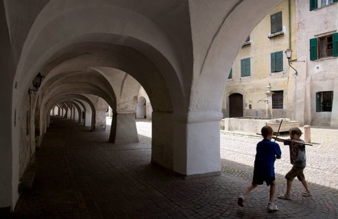 Italy S-Tyrol Neumarkt Laubengasse with view to the alleyway fountain and playing boys