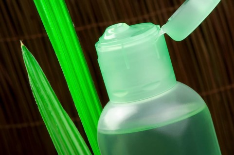 Green cosmetic bottle and green leaf. Studio shot