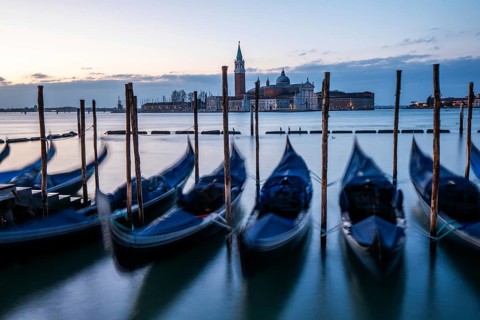 Morning light in front of sunrise, Venetian gondolas, boat dock at St Mark's Square, church of San