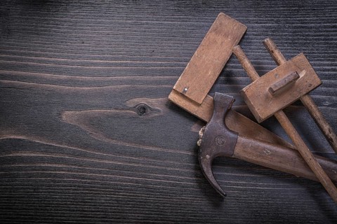 Age-old claw hammer square ruler carpenter gauge on wood board