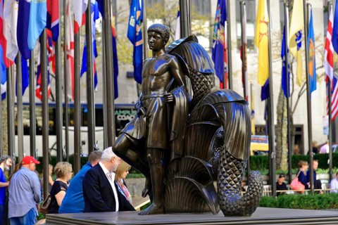 Rockefeller Center, bronze sculpture of a standing man in front of international flags, surrounded
