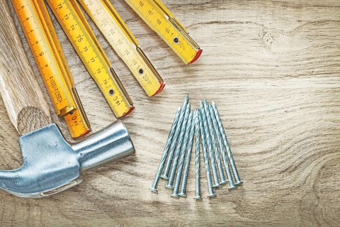 Assortment of claw hammer wooden meter construction nails on wood board building concept