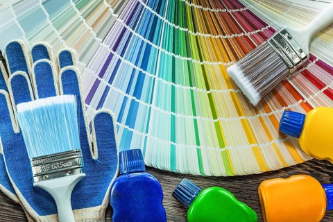 Assortment of protective gloves paint brush bottles colour palette on wooden board