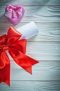 Paper roll with red bow metal present box on wooden board holidays concept