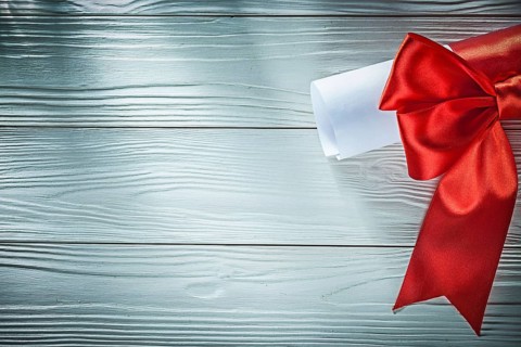 Paper roll with red ribbon on wooden board copy space