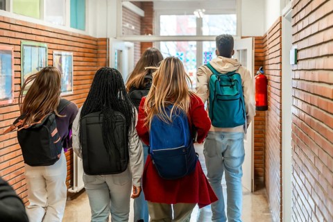 Diverse group of high school students walking together down a bustling school hallway after class,