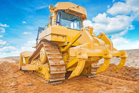 Bulldozer yellow coloured standing on sand rear view