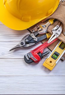 Composition of construction tooling in leather tool belt building helmet on wooden board