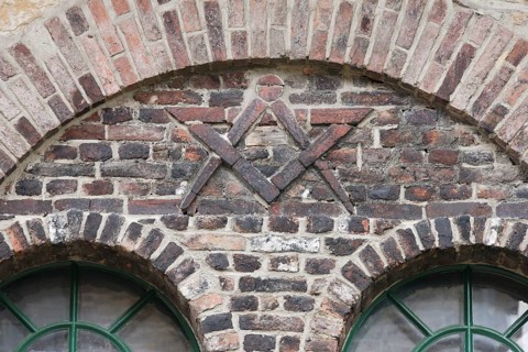 Door of the former blacksmith's workshop, wall relief with compass and drawing triangle, possibly a