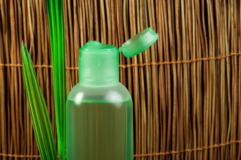 Green cosmetic bottle and green leaf. Copy space